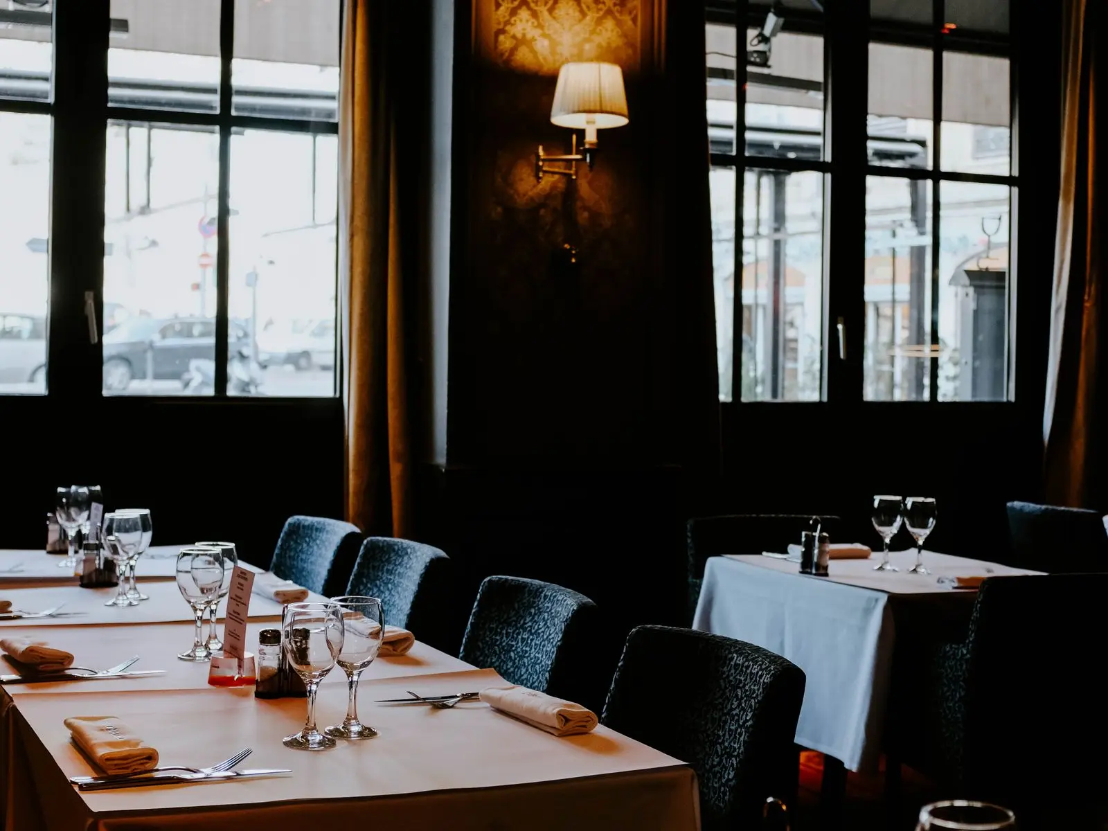 La salle de Maison Ombelle : murs vert sapin, nappes blanches et lampes dorées